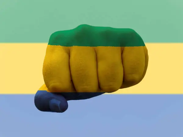 Прапор Габону зображений на людському кулаку, що представляє владу. — стокове фото