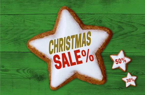 Christmas Sale cinnamon star on green wood background — Stock Photo, Image