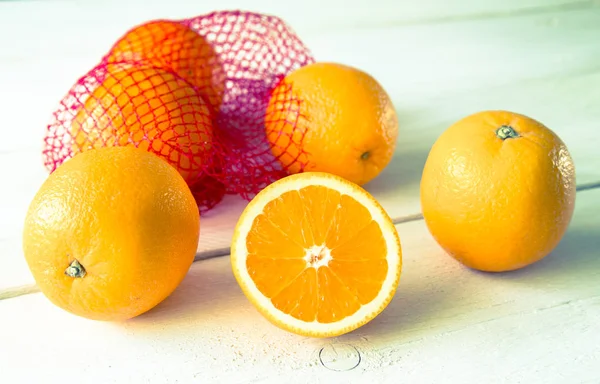 Pomarańcze na drewnianym stole w sieci — Zdjęcie stockowe