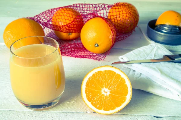 Sok pomarańczowy i pomarańczowy na drewnianym stole — Zdjęcie stockowe