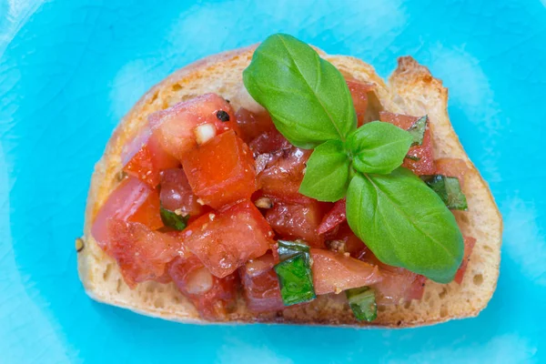 Bruschetta with tomatoes on a turquoise plate — Stock Photo, Image