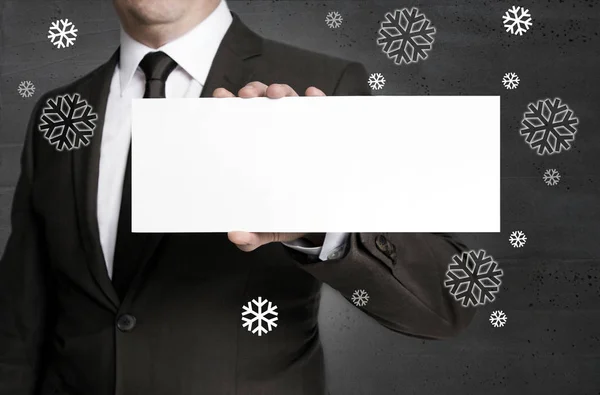 El letrero en blanco y los copos de nieve es sostenido por un hombre de negocios —  Fotos de Stock