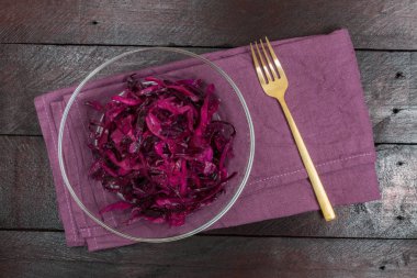 Kırmızı lahana salatası bir cam kase ve ahşap arka plan