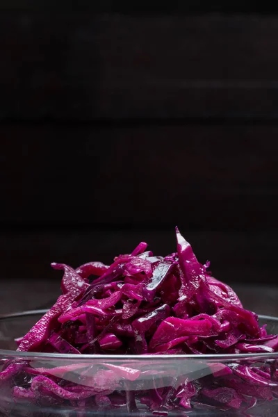 Salada de repolho vermelho em uma tigela de vidro e fundo de madeira — Fotografia de Stock