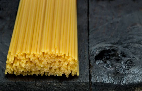 Spaghetti noodle on dark rustic wood — Stock Photo, Image