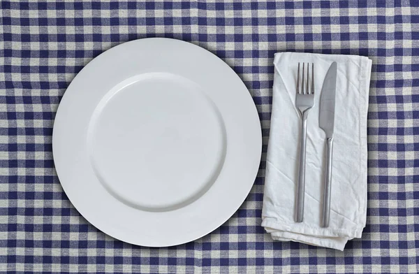 Piring kosong dan cutlery pada kain kotak-kotak biru-putih — Stok Foto