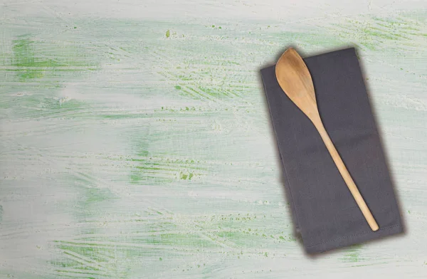 Kochlöffel und Küchentuch auf grün-weißem Holz — Stockfoto