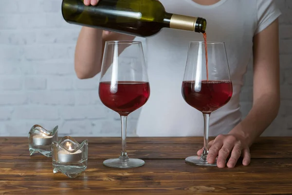 Menina jovem derramando vinho tinto em vidro na festa romântica — Fotografia de Stock