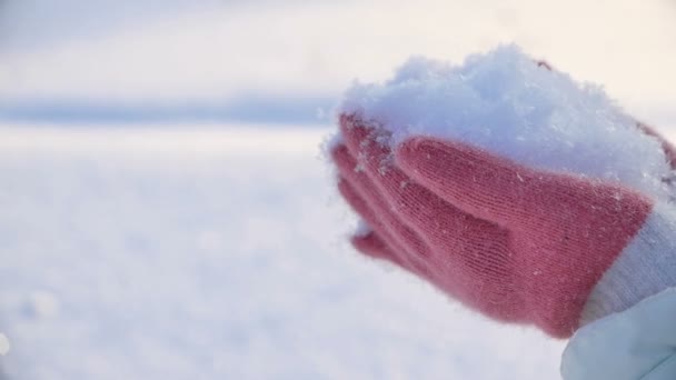 Νεαρή γυναίκα κρατώντας πατημένο χιόνι στις παλάμες και να φυσάει — Αρχείο Βίντεο