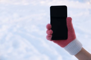 Kadın el eldiven ile smartphone üstünde kar