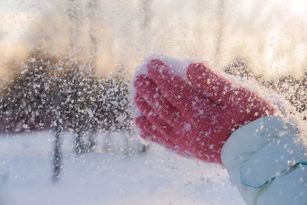 Junge Frau hält Schnee auf Palmen und pustet ihn — Stockfoto