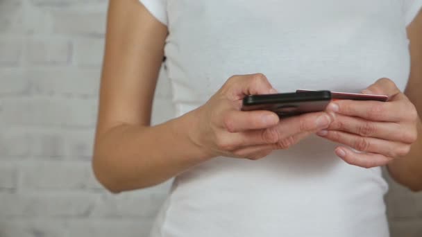 Mãos segurando cartão de crédito e digita o número em um smartphone. Movimento lento — Vídeo de Stock