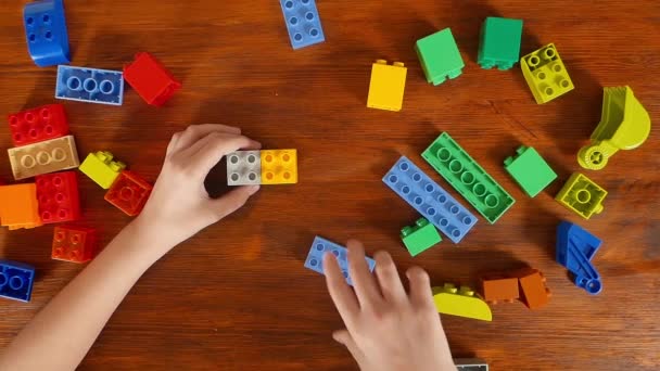 Meisje in de gekleurde blokken aan de tafel spelen — Stockvideo
