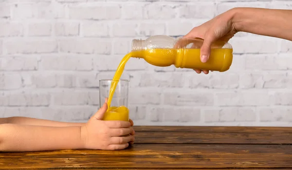 Moeder sommige sinaasappelsap in glas uit fles gieten — Stockfoto