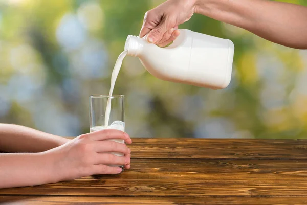 Moeders handen houden en melk in het glas gieten — Stockfoto