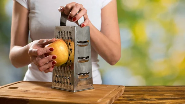 Gros plan d'une femme qui râpe une pomme mûre . — Photo