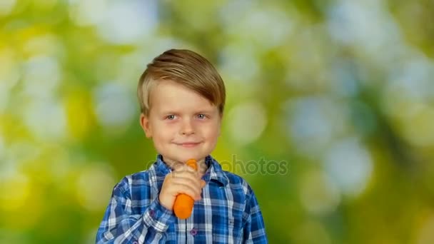 Χαριτωμένο μικρό αγόρι τρώει καρότο και χαμογελαστός — Αρχείο Βίντεο