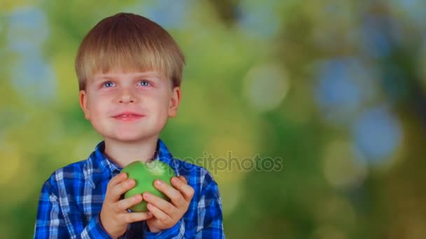 Roztomilý malý chlapec jíst zelené jablko a usmívá se