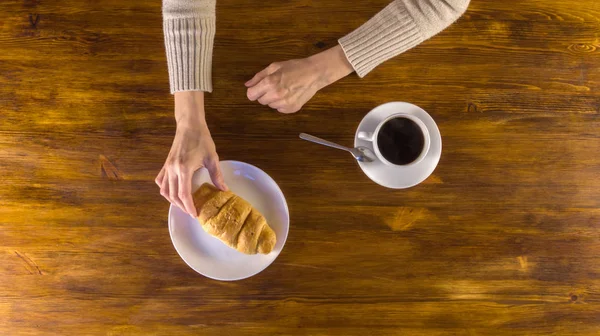 Женщина пьет черный кофе с круассаном на завтрак — стоковое фото