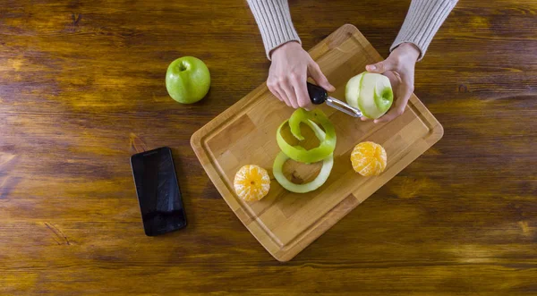 Woman peeling green apple with peeler — Stock Photo, Image