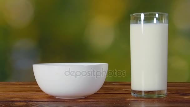 Primer plano de los copos de cereales vertiendo en un tazón sobre una mesa de madera — Vídeos de Stock