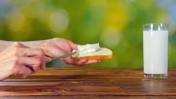 Meisje zetten kaas op brood en drinken melk — Stockvideo