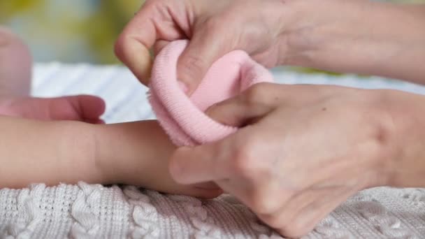 Мама надевает розовые носки на детские лапки — стоковое видео