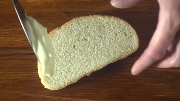 Nahaufnahme 4k-Video: Frau verteilt cremige Butter auf ein Stück Brot — Stockvideo