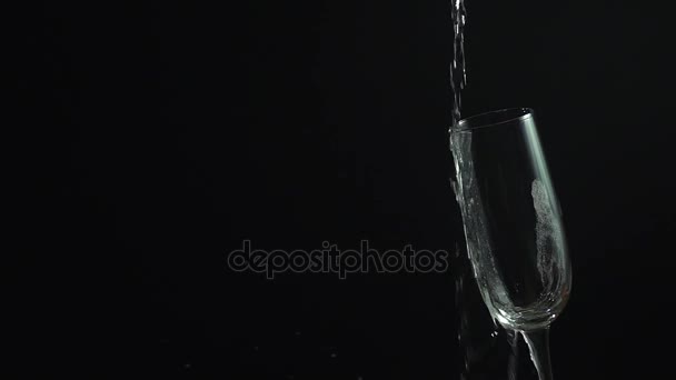 Champagne pouring from bottle into glass on black, slow motion hd video — Stock Video