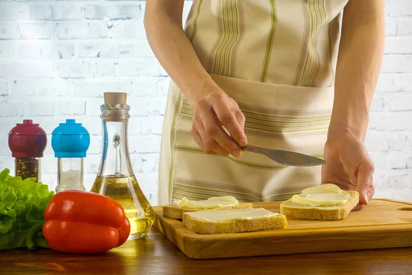 Mujer preparando sándwiches y unta mantequilla en el pan — Foto de Stock