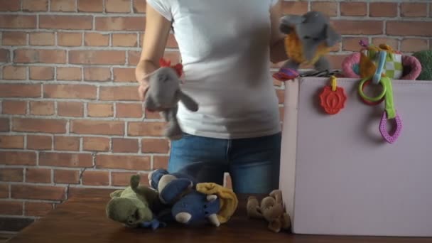 Tienda de caridad. Mujer clasificando juguetes usados que donaron a ella, video en cámara lenta — Vídeo de stock