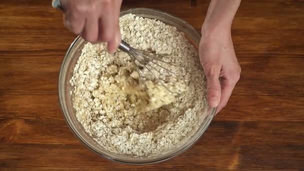 Woman make dough for oatmeal cookies in glass bowl, top view slow motion video — Stock Video