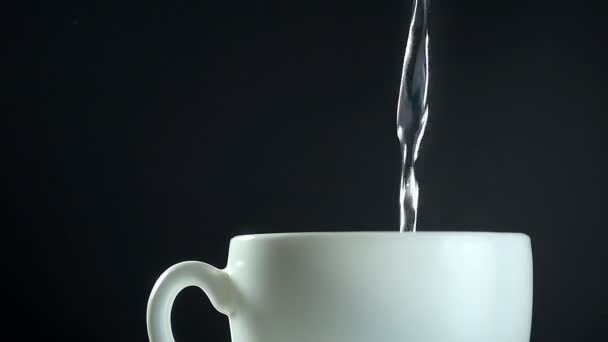 Pouring boiling water to white mug on black baground, close-up slow motion video — Stock Video