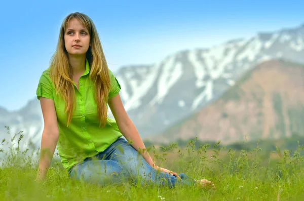 Beautiful woman is laying on the grass in Tien-Shan mountains — Stock Photo, Image
