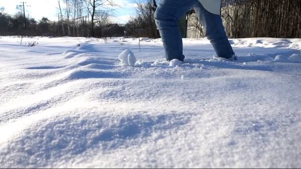 Женщина в белых сапогах и джинсах находится в глубоком снегу, замедленной съемки hd видео — стоковое видео