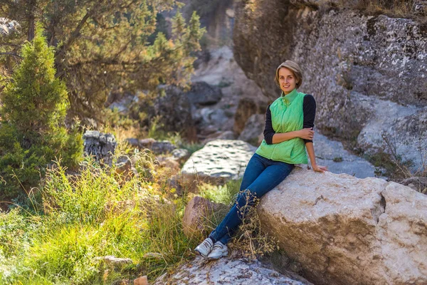 Girl in the mountains resting on a rock — Stock Photo, Image