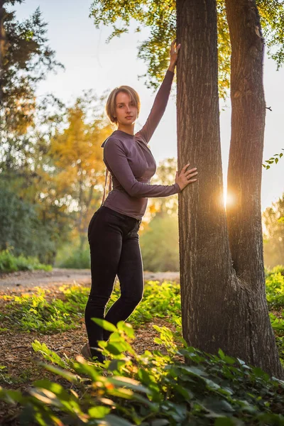 Beautiful model near tree in the forest at sunset — Stock Photo, Image