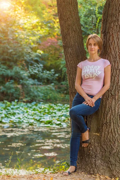 Женщина возле деревьев в розовой футболке — стоковое фото