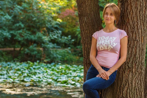 Gün batımında pembe tişört ağaçlarda yakınındaki şanslı kadın — Stok fotoğraf