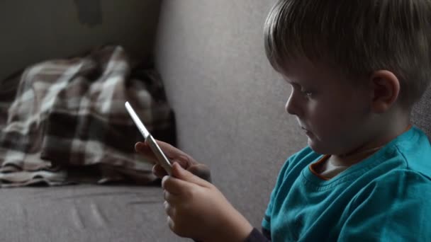 Lindo niño jugando con la tableta en el sofá — Vídeo de stock