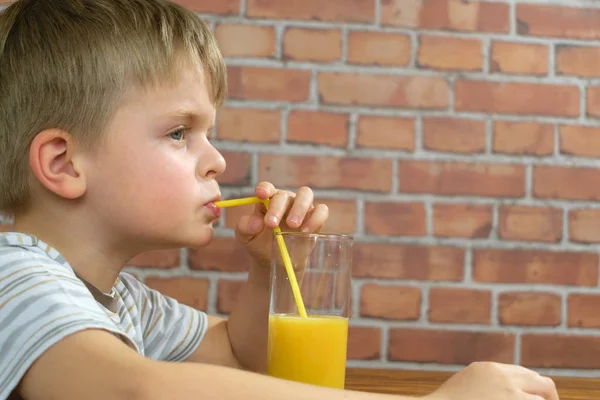 Baby trinkt Orangensaft aus Glas — Stockfoto