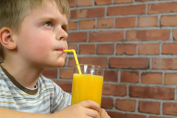 Niño beber zumo de naranja delicioso fresco de paja — Foto de Stock