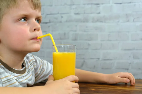 Kleiner Junge hat Orangensaft zum Frühstück — Stockfoto