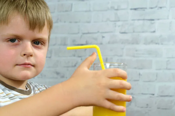 Kleiner Junge mit einem Glas Orangensaft auf weißem Hintergrund — Stockfoto