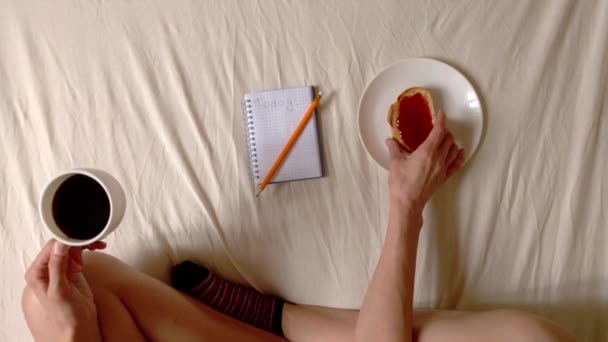 Frau isst Toast und schmiedet Pläne am Tag, von oben gesehen hd video — Stockvideo