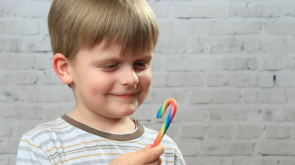 Kleiner Junge isst bunte Bonbons auf weißem Hintergrund — Stockfoto