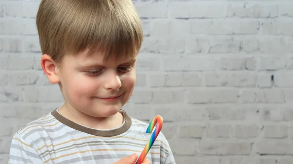 Little boy looking on colorful candy in his hands — Stock Photo, Image
