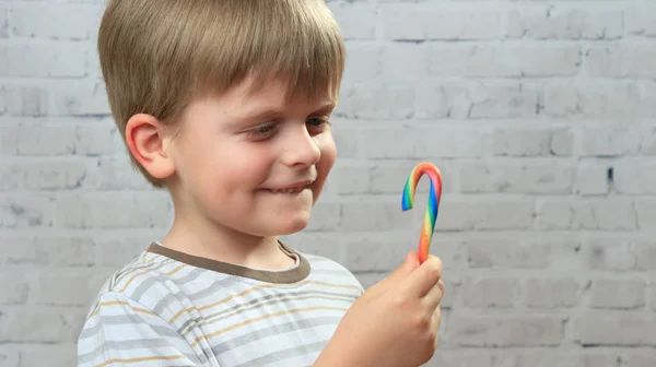 Funny boy is looking on sweet candy in his hand — Stock Photo, Image