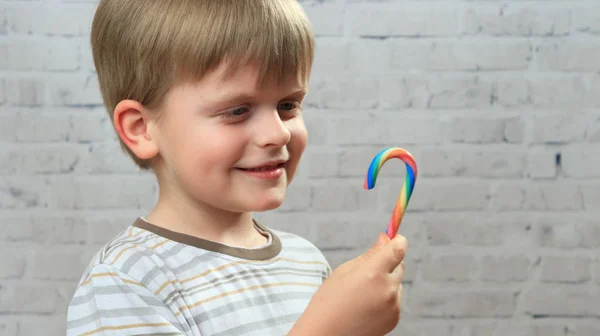 Funny kid eating yummy colorful candy at home — Stock Photo, Image