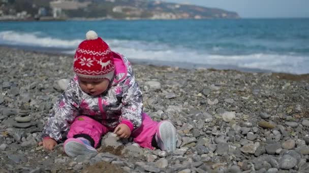 Petite fille mignonne jouant sur la plage avec des cailloux, ralenti vidéo HD — Video